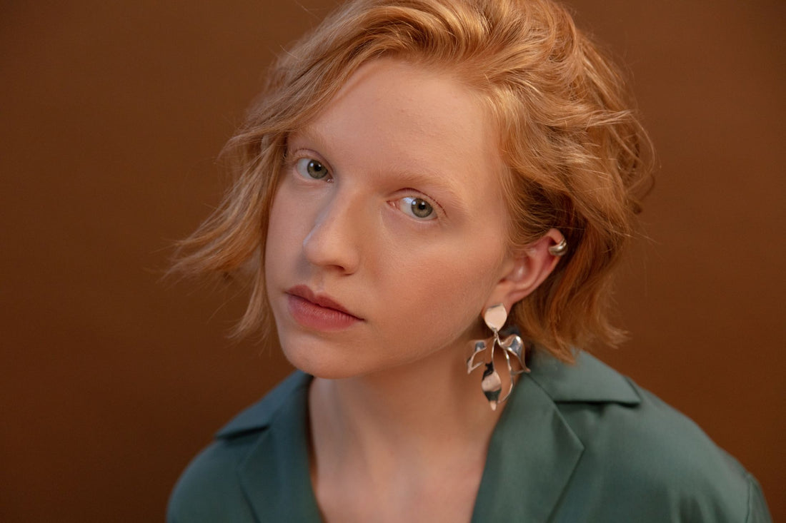 Portrait with sculptural silver earrings and a green shirt