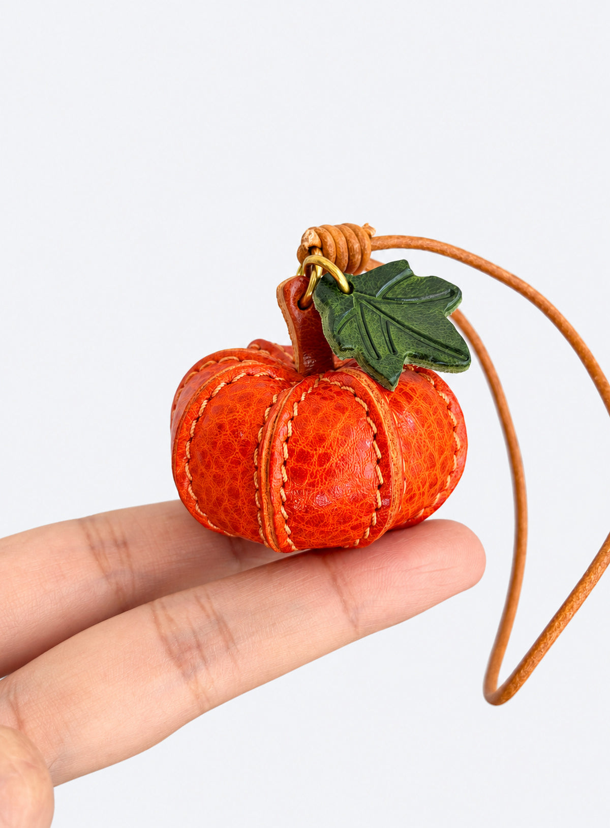 Pumpkin-shaped leather bag charm with stitched panels, a leaf accent, and a hanging loop (Pumpkin Orange)