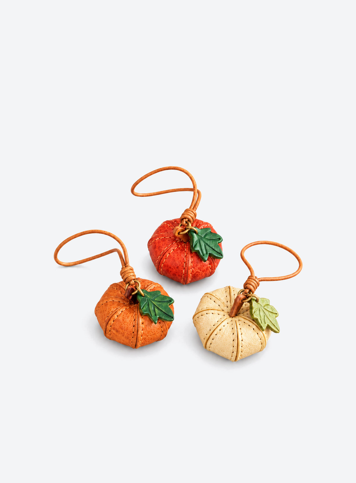 Pumpkin-shaped leather bag charm with stitched panels, a leaf accent, and a hanging loop