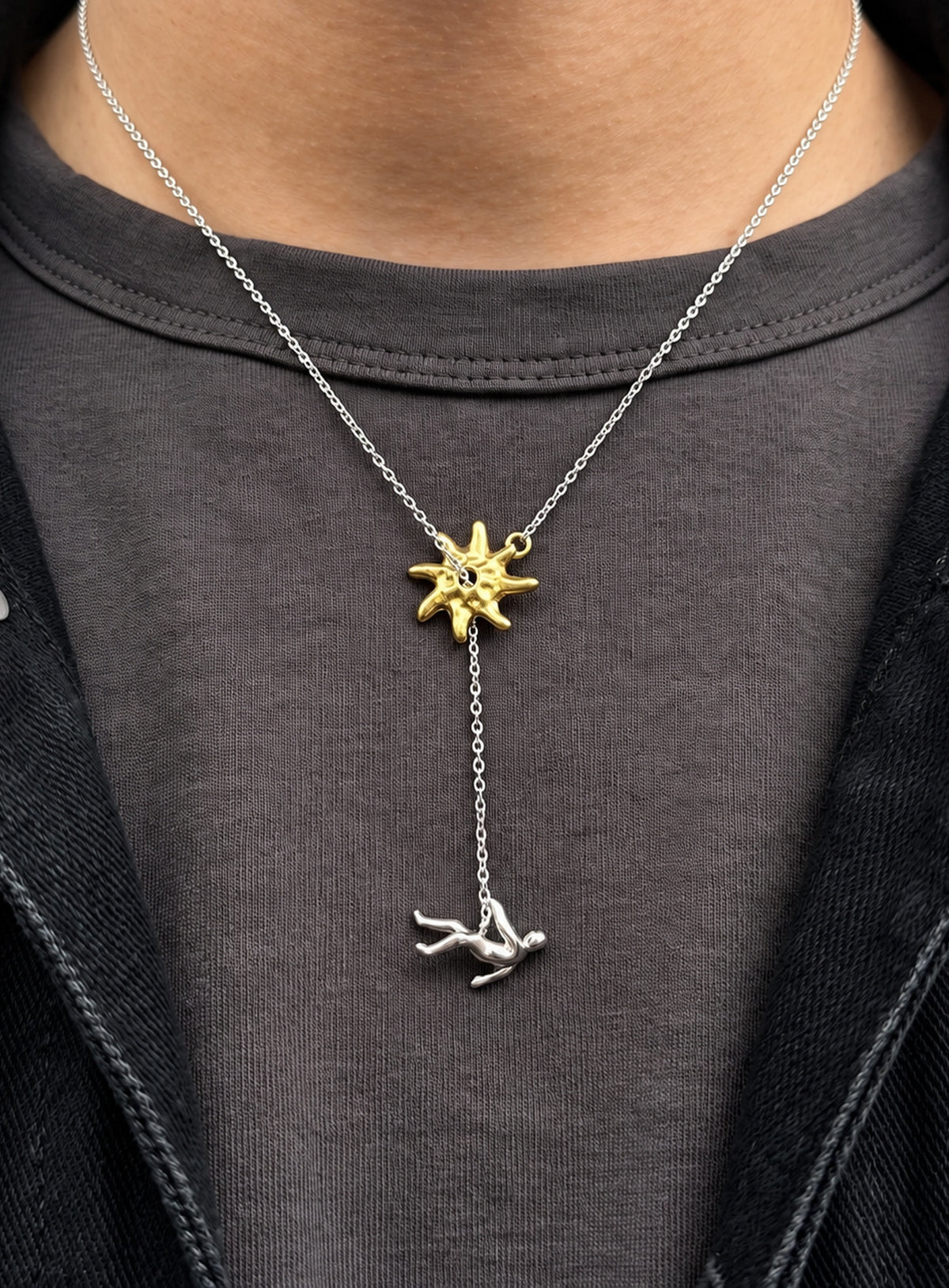 Y-shaped necklace with a hammered sunburst above a small falling figure