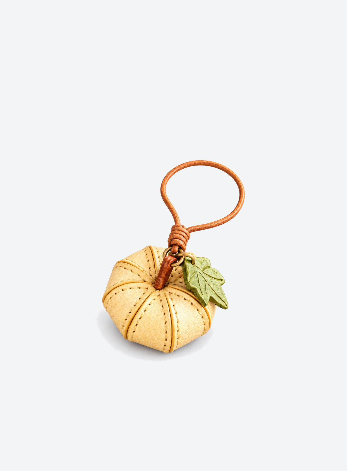 Pumpkin-shaped leather bag charm with stitched panels, a leaf accent, and a hanging loop (Harvest Cream)