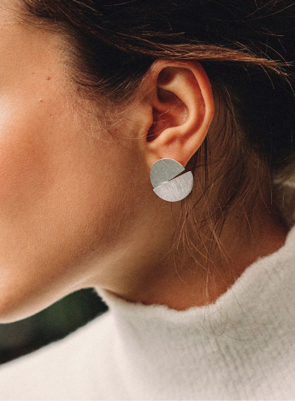 Close-up of an ear wearing a silver earring with a geometric design (Silver)
