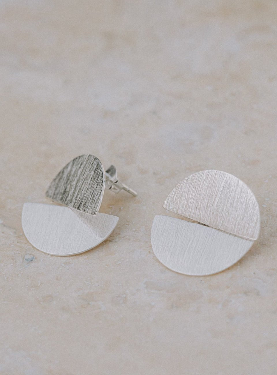 Pair of silver earrings on a beige surface (Silver)
