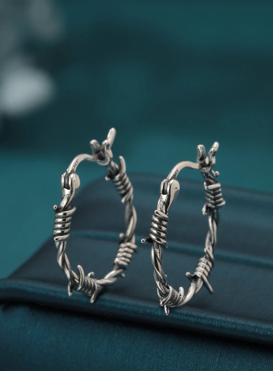 Silver hoop earrings on a teal surface