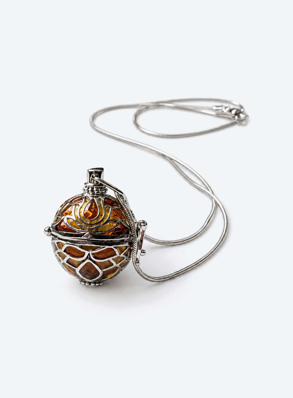 Amber-tone orb pendant necklace with silver-tone filigree cage and chain on a light studio background