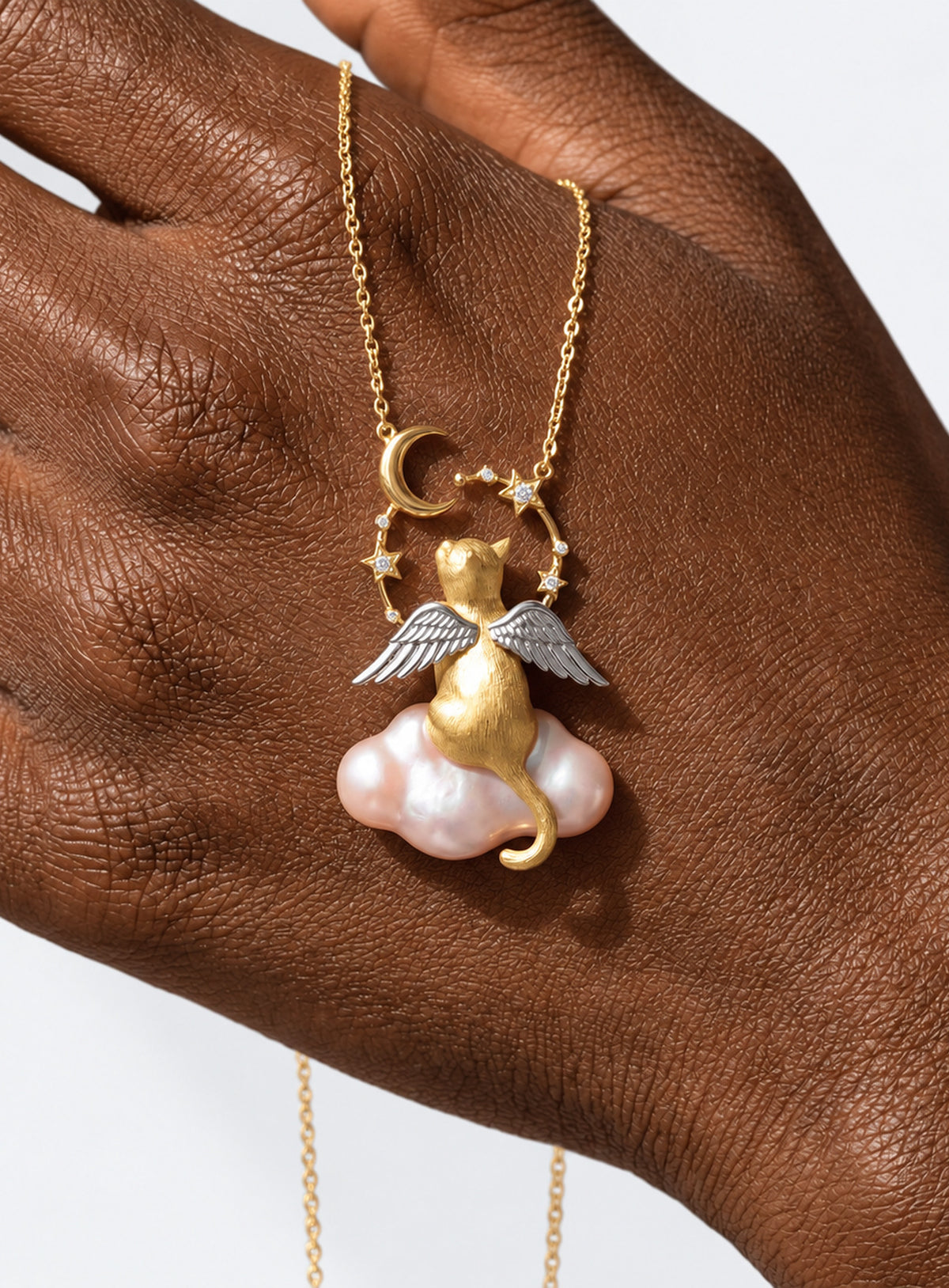 Necklace with a winged cat pendant sitting on a baroque-style pearl cloud with moon and star accents