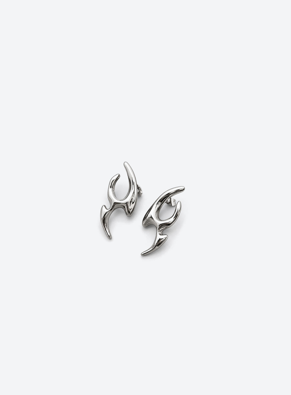 Pair of asymmetric stud earrings with curved points, open cutouts, and a polished silver appearance