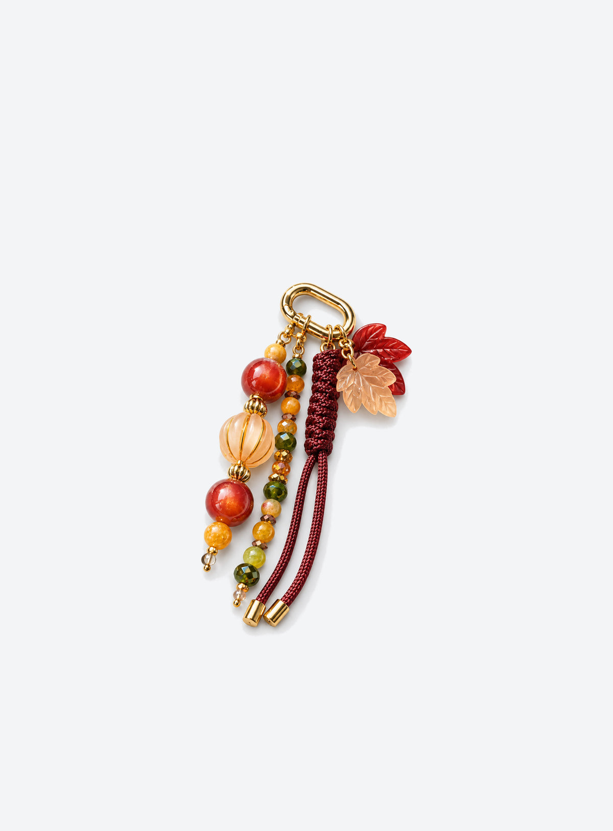Bag charm with two leaf charms, red and amber-colored beads, burgundy woven cord and a gold-tone clasp