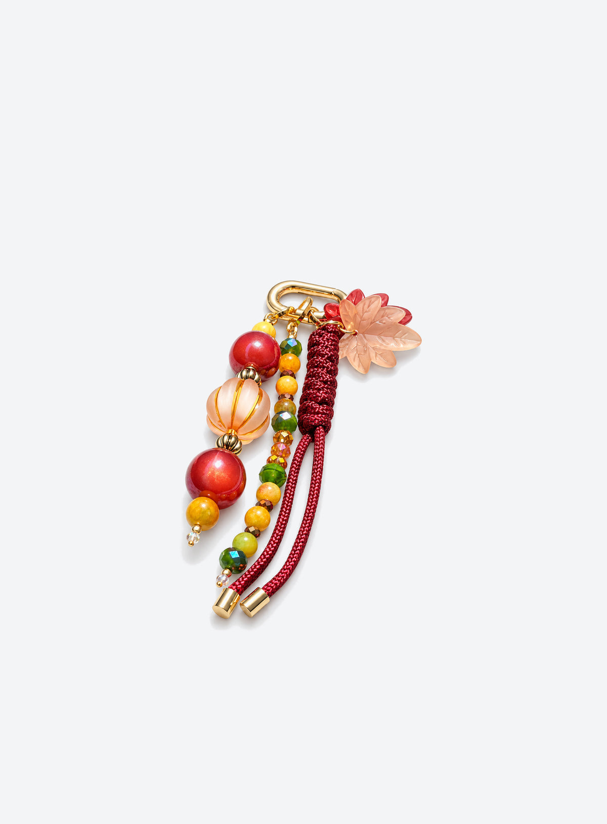 Bag charm with two leaf charms, red and amber-colored beads, burgundy woven cord and a gold-tone clasp
