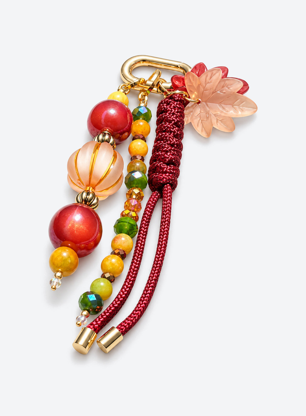Bag charm with two leaf charms, red and amber-colored beads, burgundy woven cord and a gold-tone clasp
