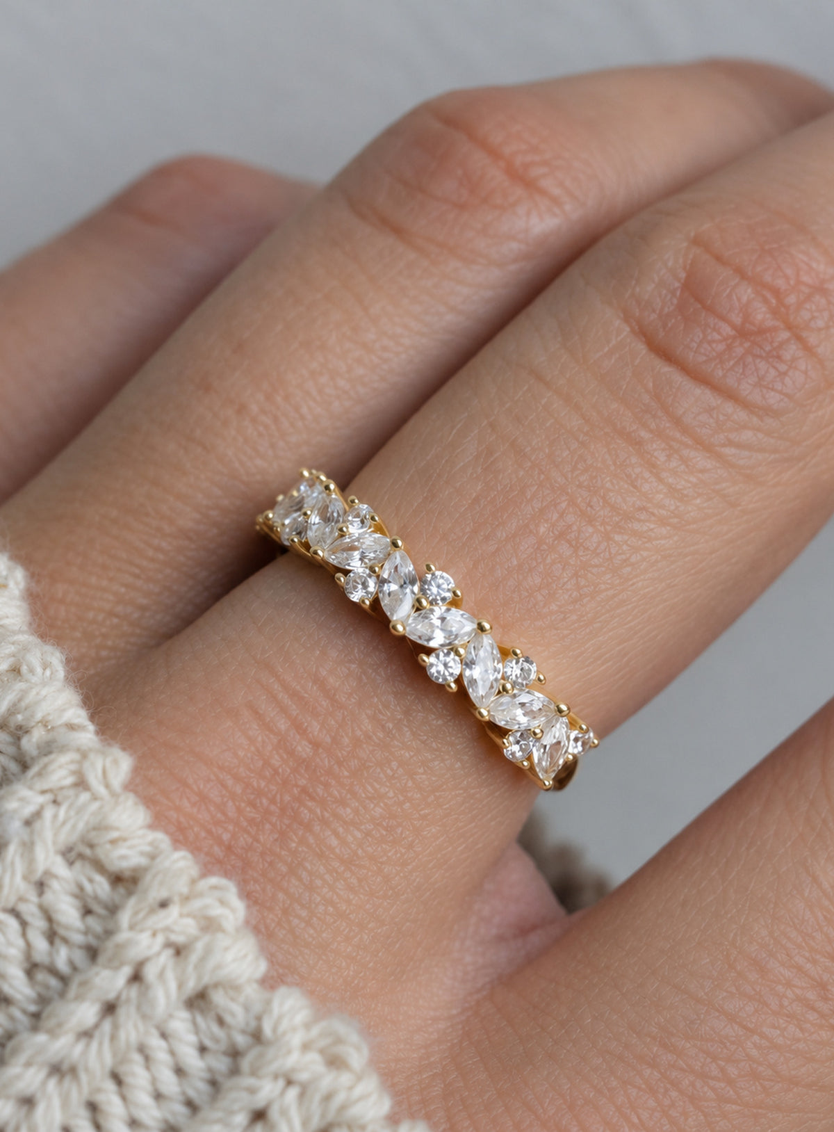 Gold-tone ring with mixed-shape clear cubic zirconia stones across the front and a slender plain band at the back