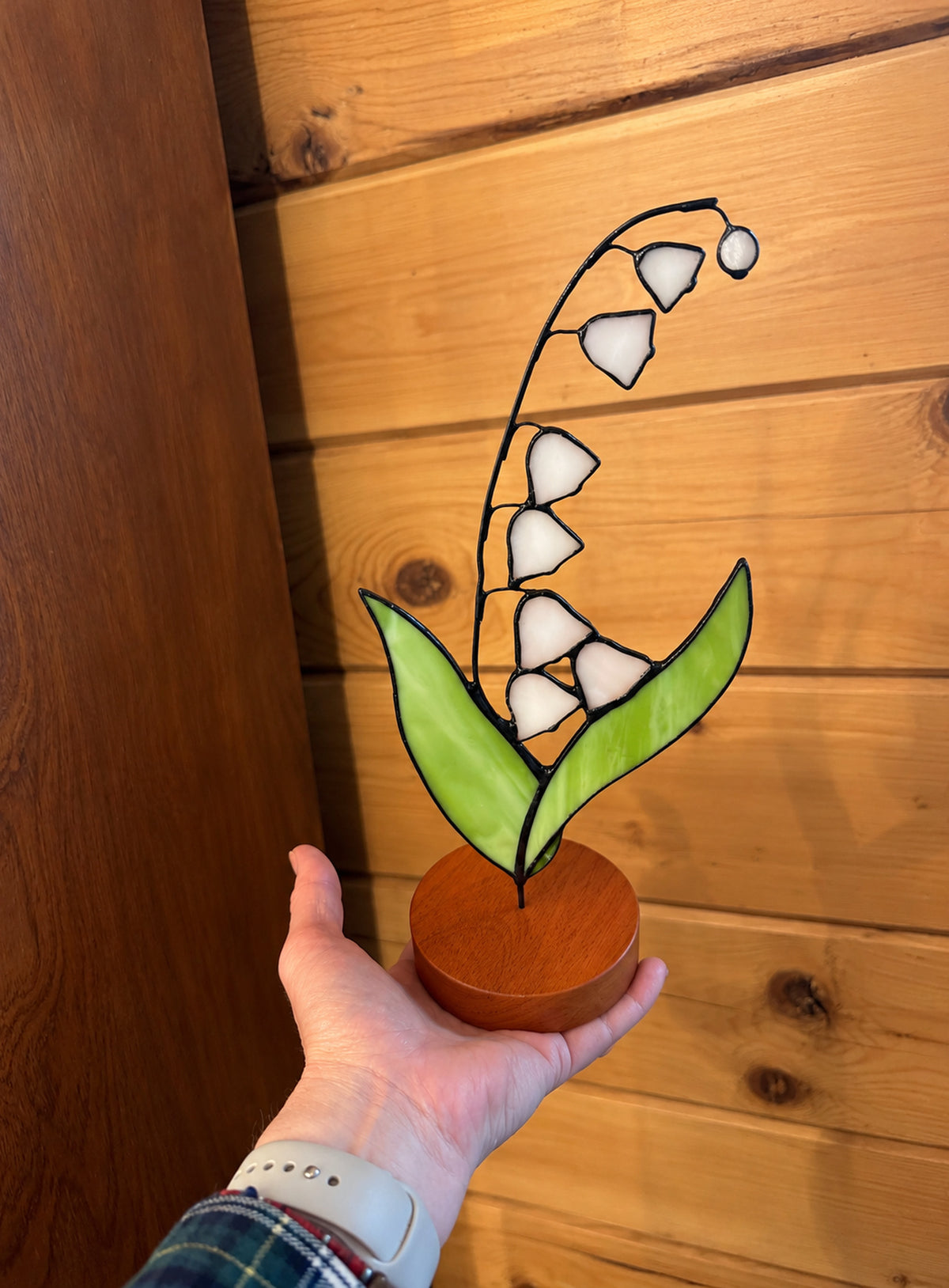Freestanding colored-glass birth month flower with a round display base, photographed on a studio background. (May)