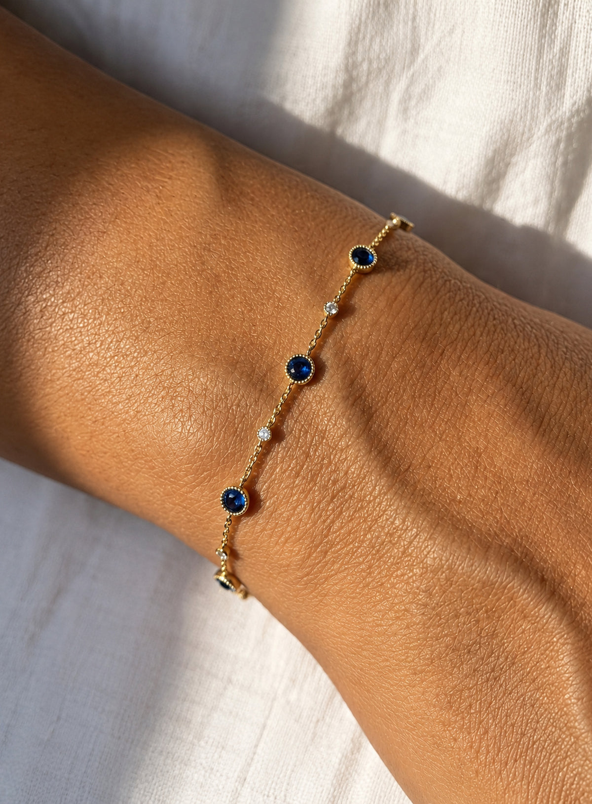 Blue and clear stone station bracelet with round settings and a delicate adjustable chain (Gold)