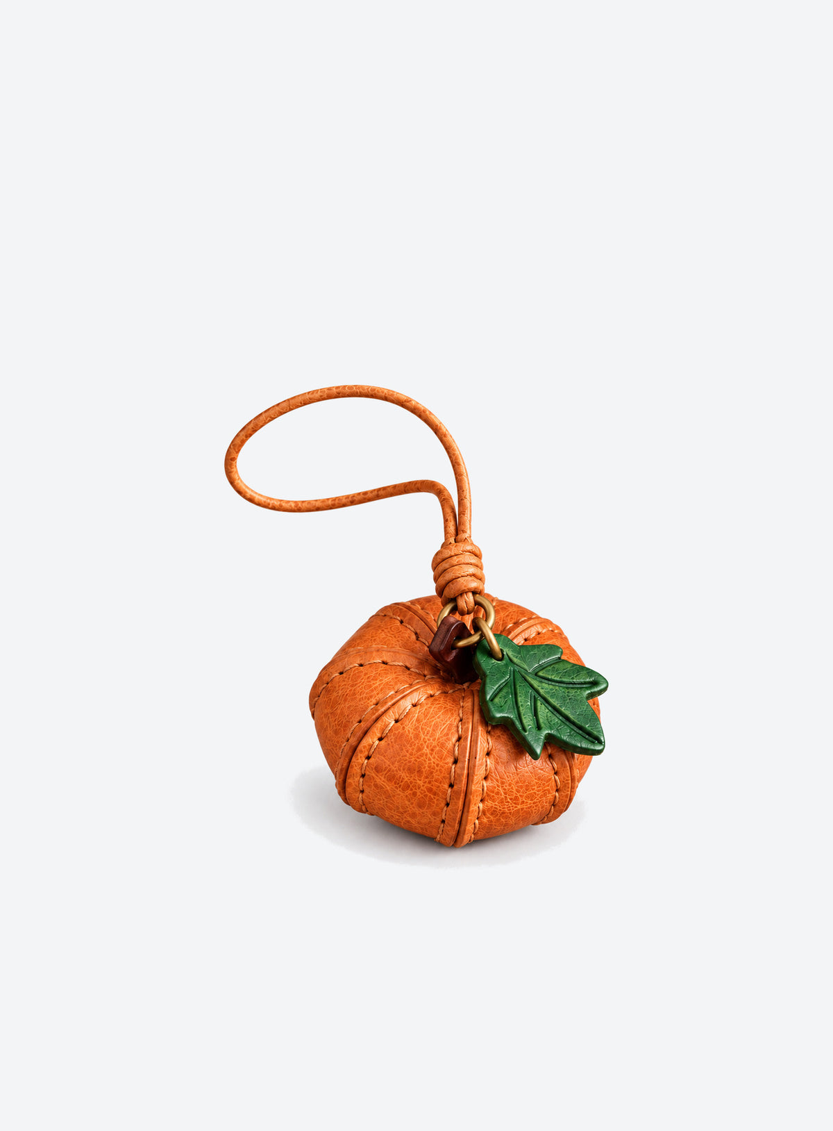 Pumpkin-shaped leather bag charm with stitched panels, a leaf accent, and a hanging loop (Cognac Brown)