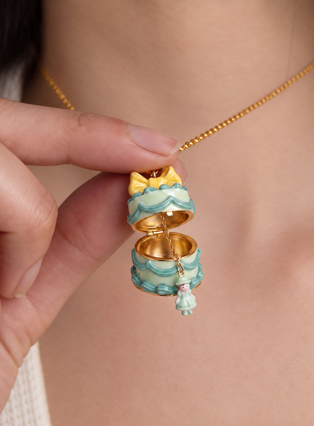 Cake-shaped necklace pendant with a bow, opening to reveal a small doll charm attached by a fine chain (Green Cake)