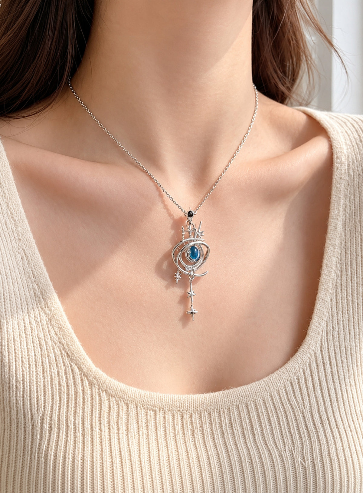 Armillary sphere pendant with nested rings, a blue center stone, celestial markings, and dangling stars