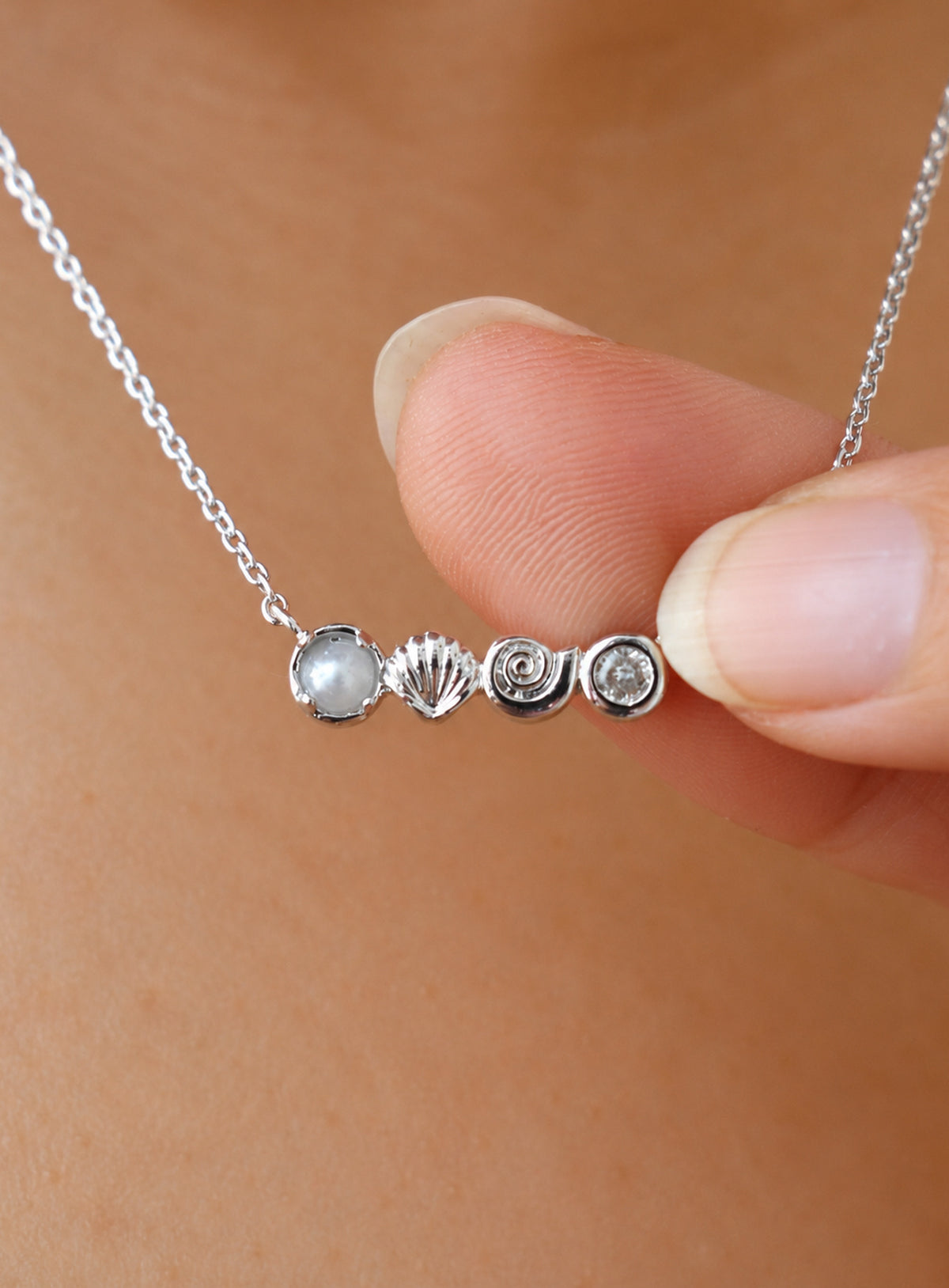 Delicate necklace with conch and scallop shell charms, a faux pearl and clear accents (Silver)
