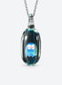 Rounded clear glass ghost pendant with large outlined eyes, small pale highlights, and a silver-tone chain