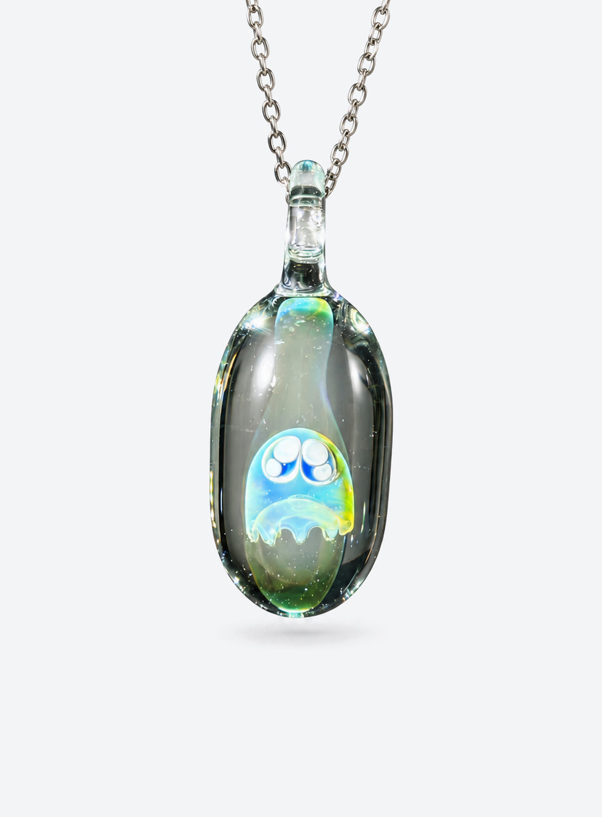 Rounded clear glass ghost pendant with large outlined eyes, small pale highlights, and a silver-tone chain