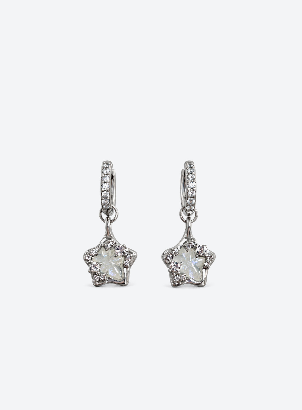 Silver-tone stone-set huggie hoops with clear asymmetrical five-point star drops and small crystal accents