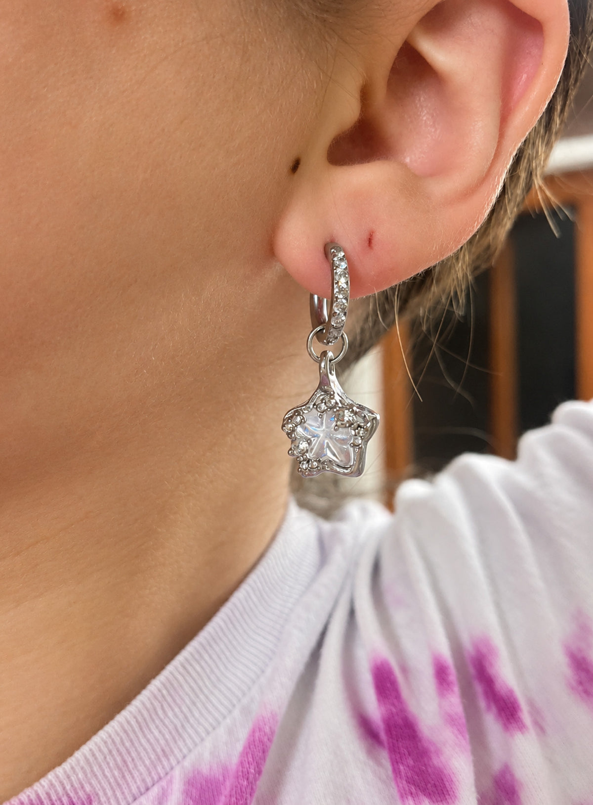 Silver-tone stone-set huggie hoops with clear asymmetrical five-point star drops and small crystal accents