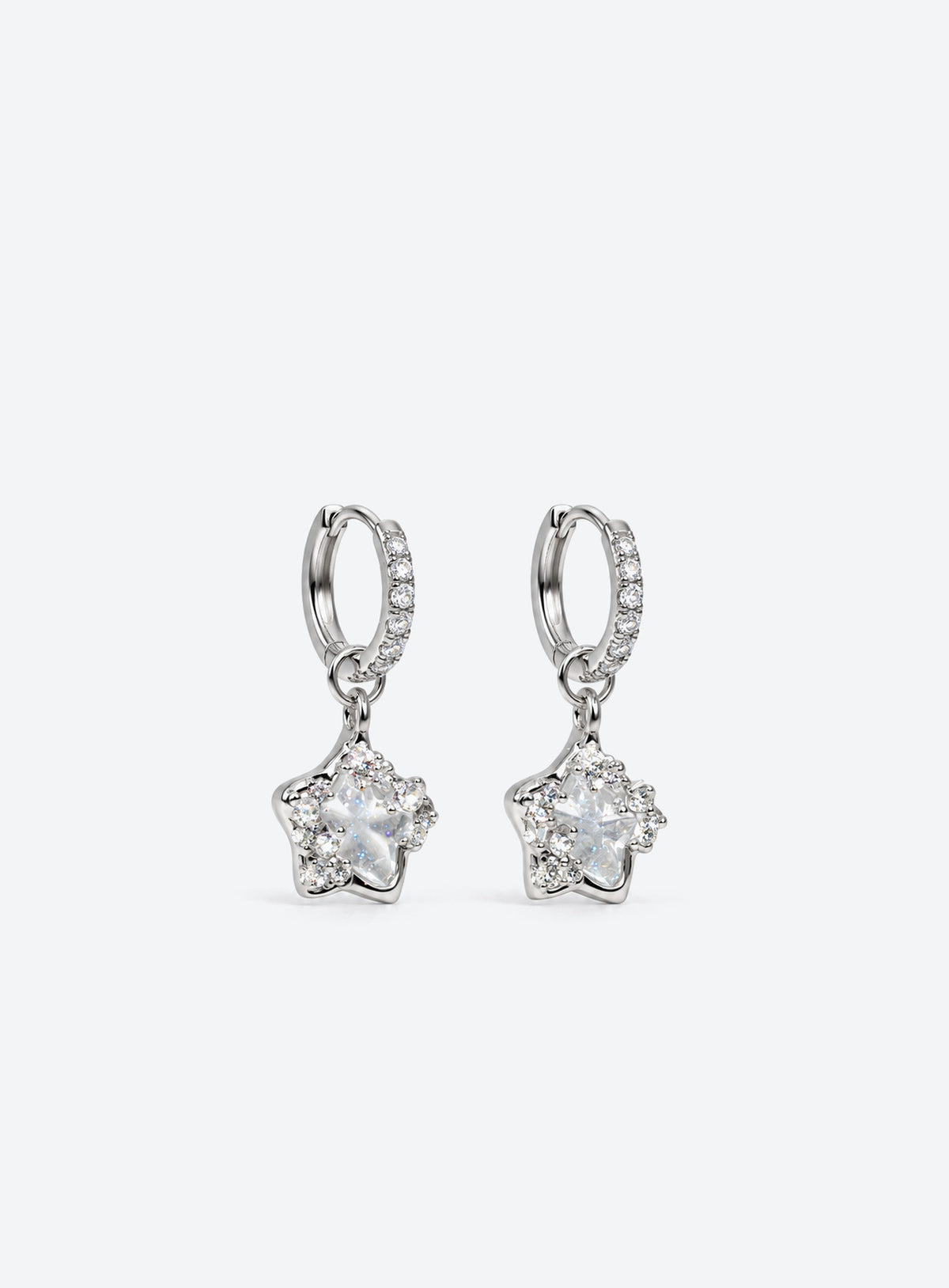 Silver-tone stone-set huggie hoops with clear asymmetrical five-point star drops and small crystal accents