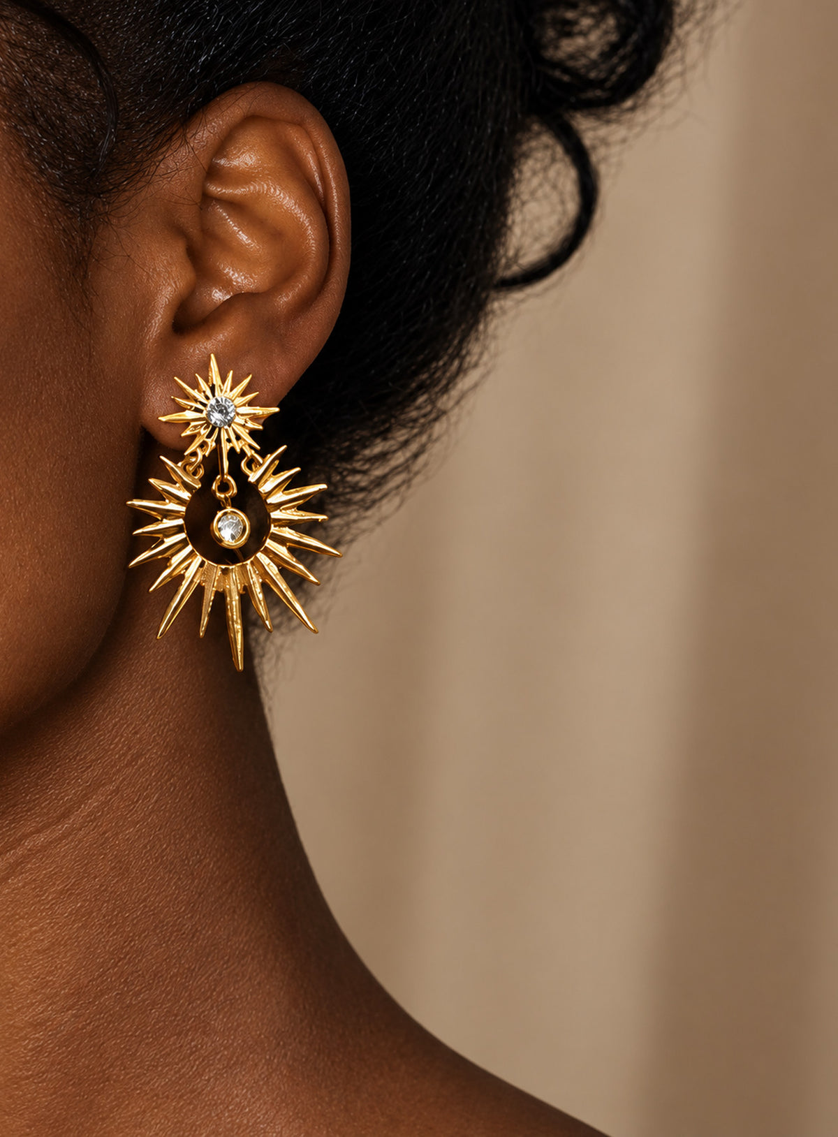 Gold-tone sunburst drop earrings with crystal-centered tops, open radiating circles, and suspended clear crystals
