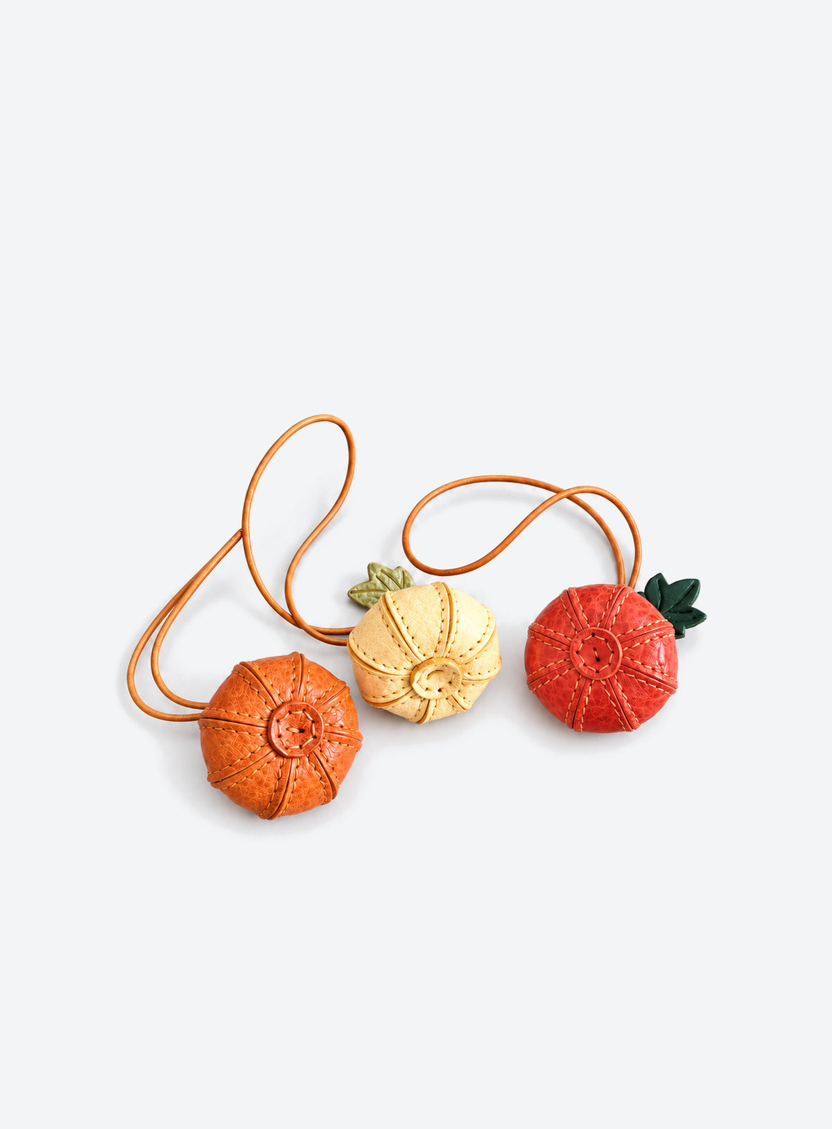 Pumpkin-shaped leather bag charm with stitched panels, a leaf accent, and a hanging loop