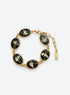Linked oval bracelet charms with white dried flowers on black backgrounds and decorative vintage-inspired frames
