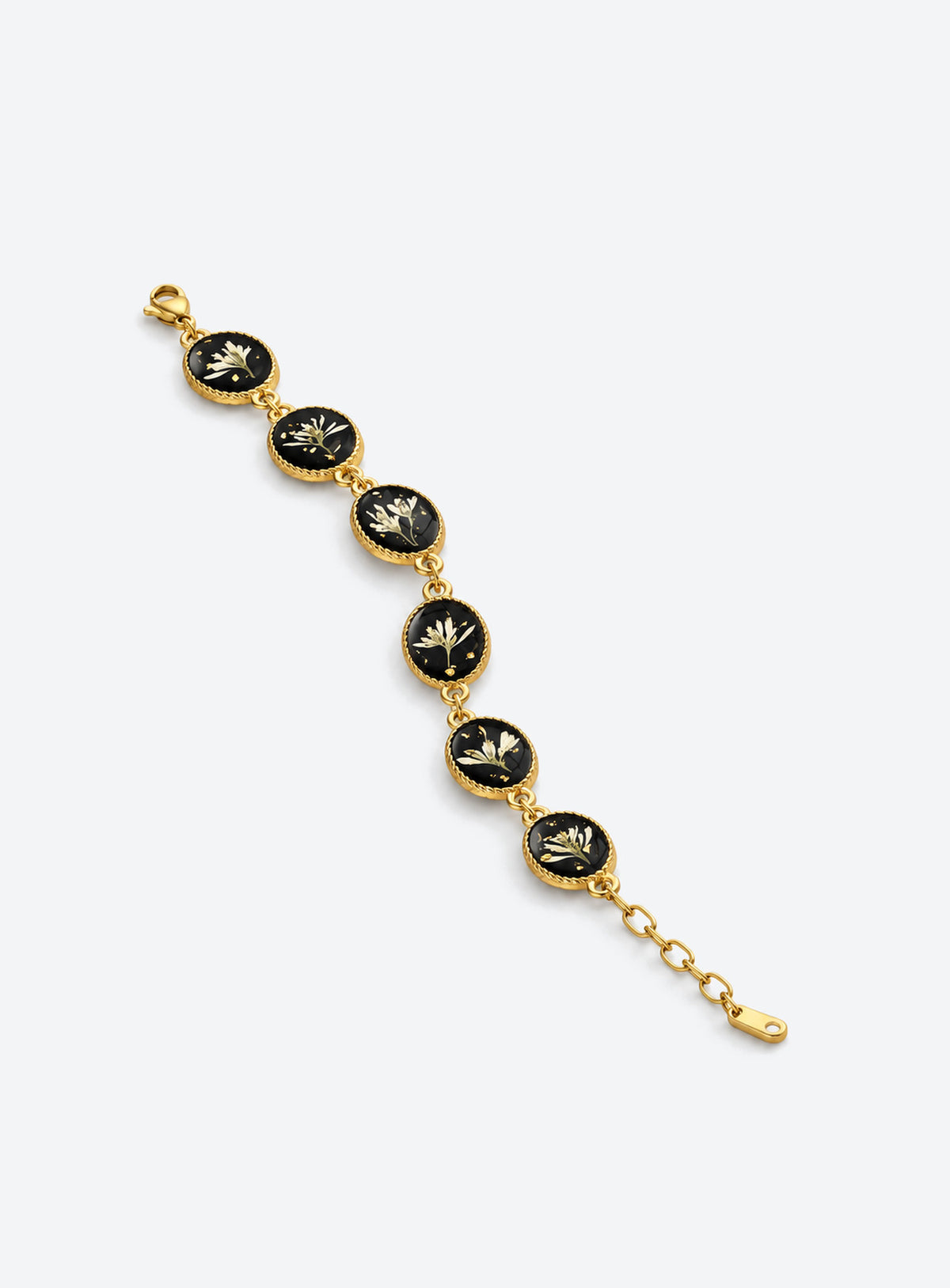 Linked oval bracelet charms with white dried flowers on black backgrounds and decorative vintage-inspired frames