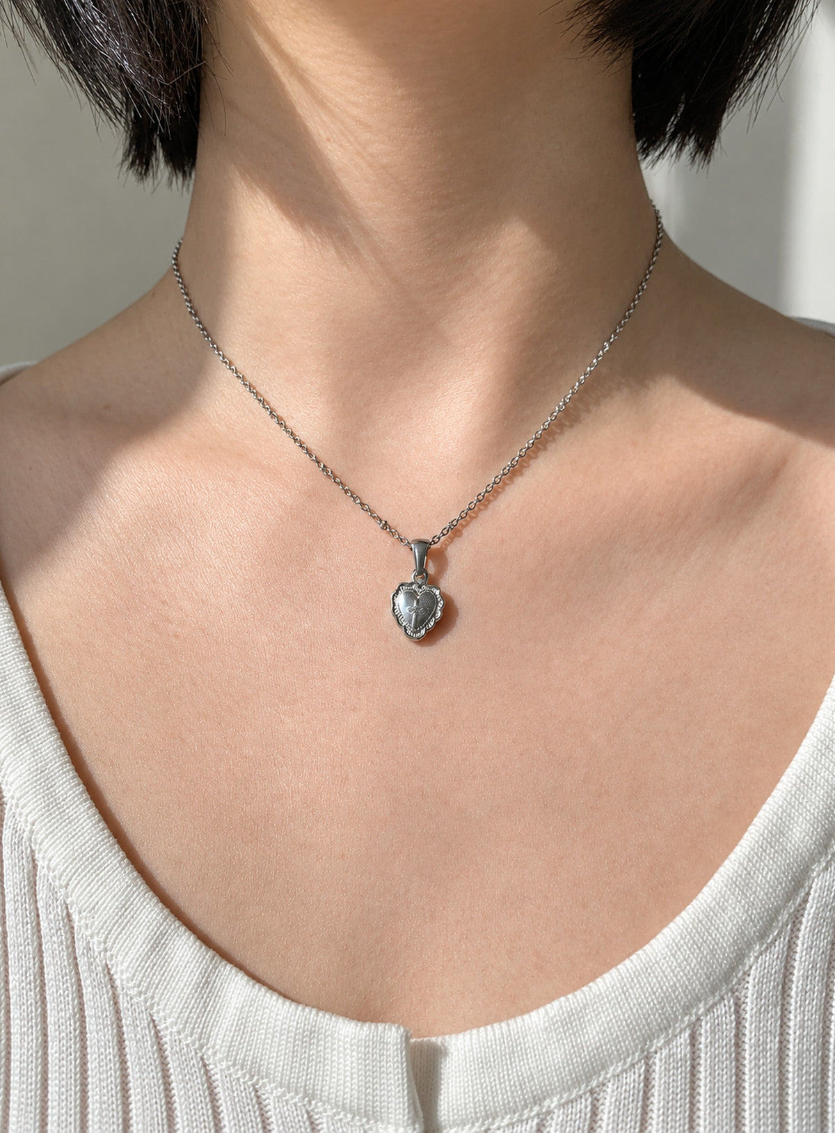 Silver-tone fine chain necklace with engraved heart pendant and raised reflective metal centre