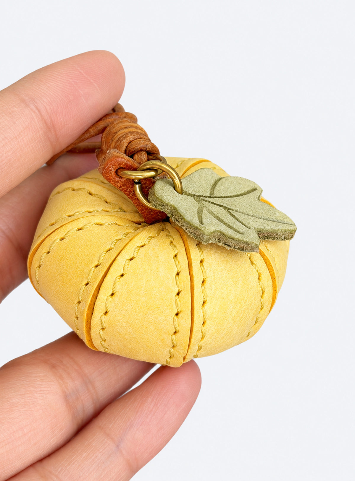Pumpkin-shaped leather bag charm with stitched panels, a leaf accent, and a hanging loop (Harvest Cream)