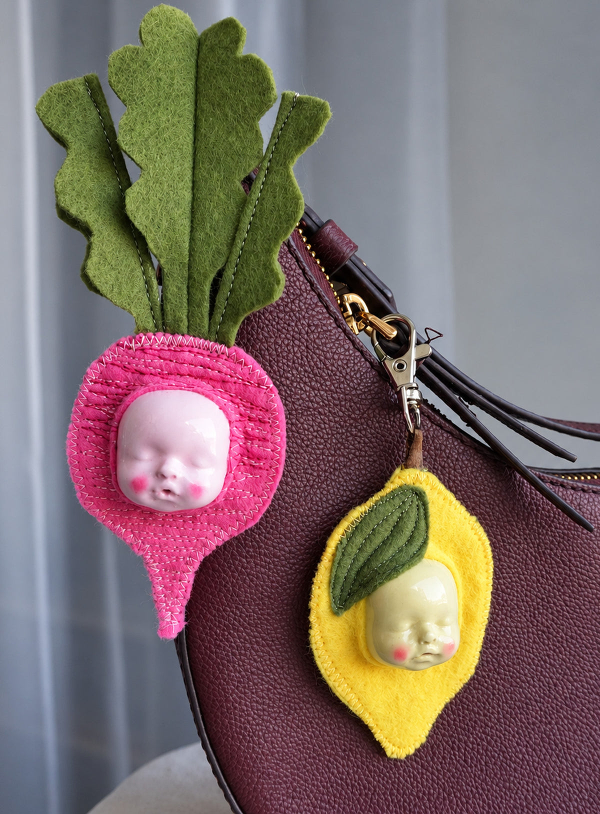Handmade orange-shaped felt bag charm with a sculpted baby face, green leaves and a metal clasp