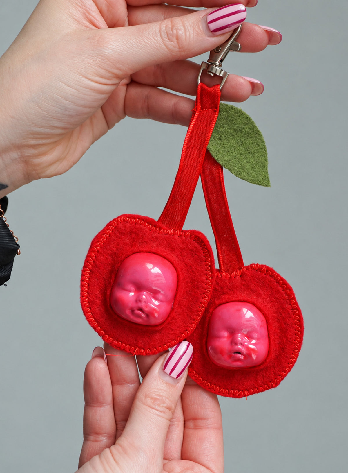 Handmade orange-shaped felt bag charm with a sculpted baby face, green leaves and a metal clasp