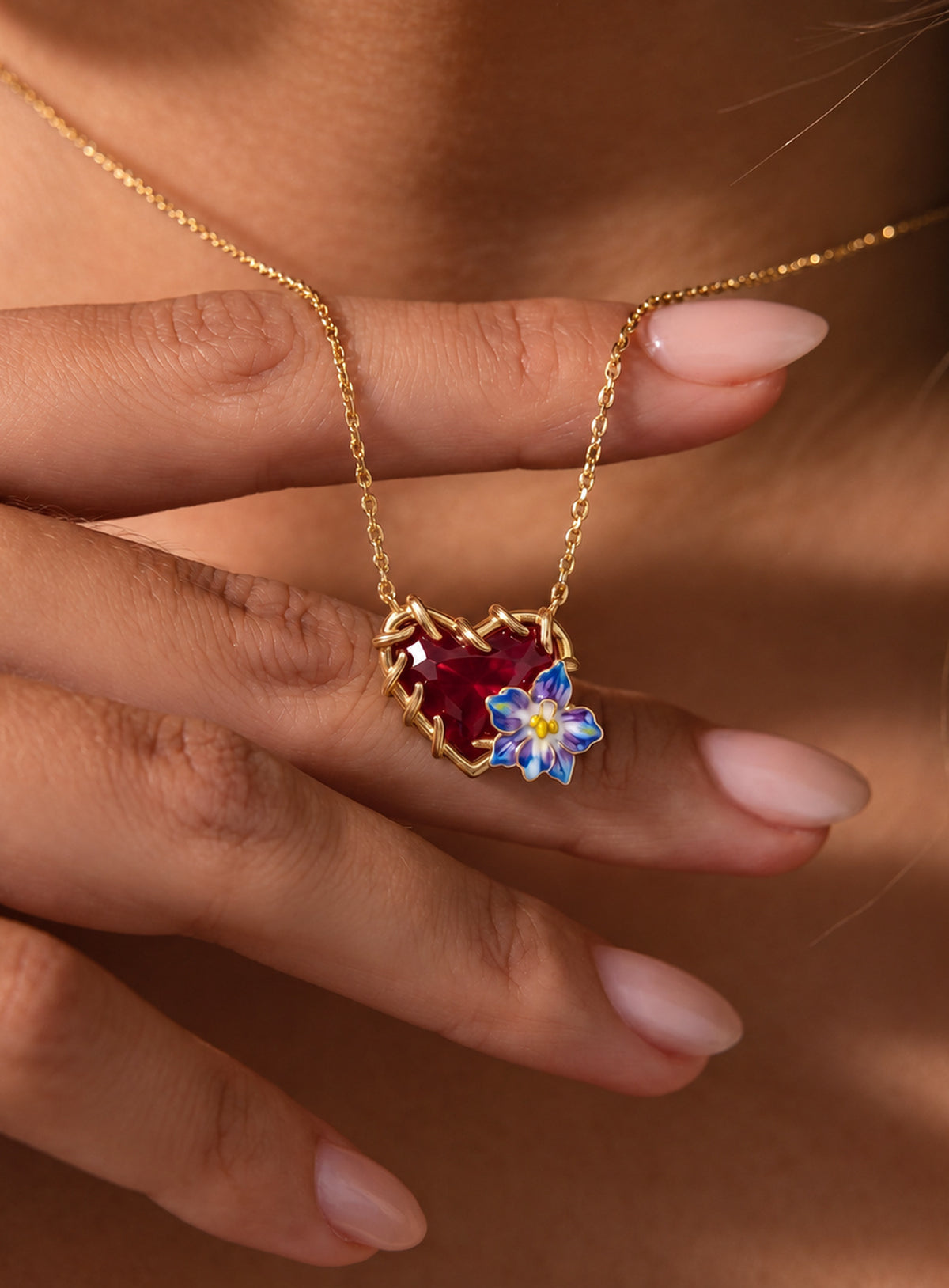 Heart-shaped crystal pendant necklace with enameled floral details and a gold-tone vine frame (July)