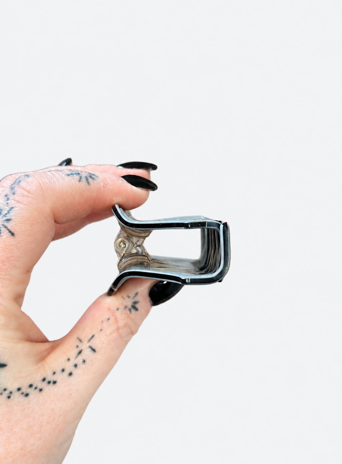 Small grey acetate hair claw with a winged skull design and dark outlines