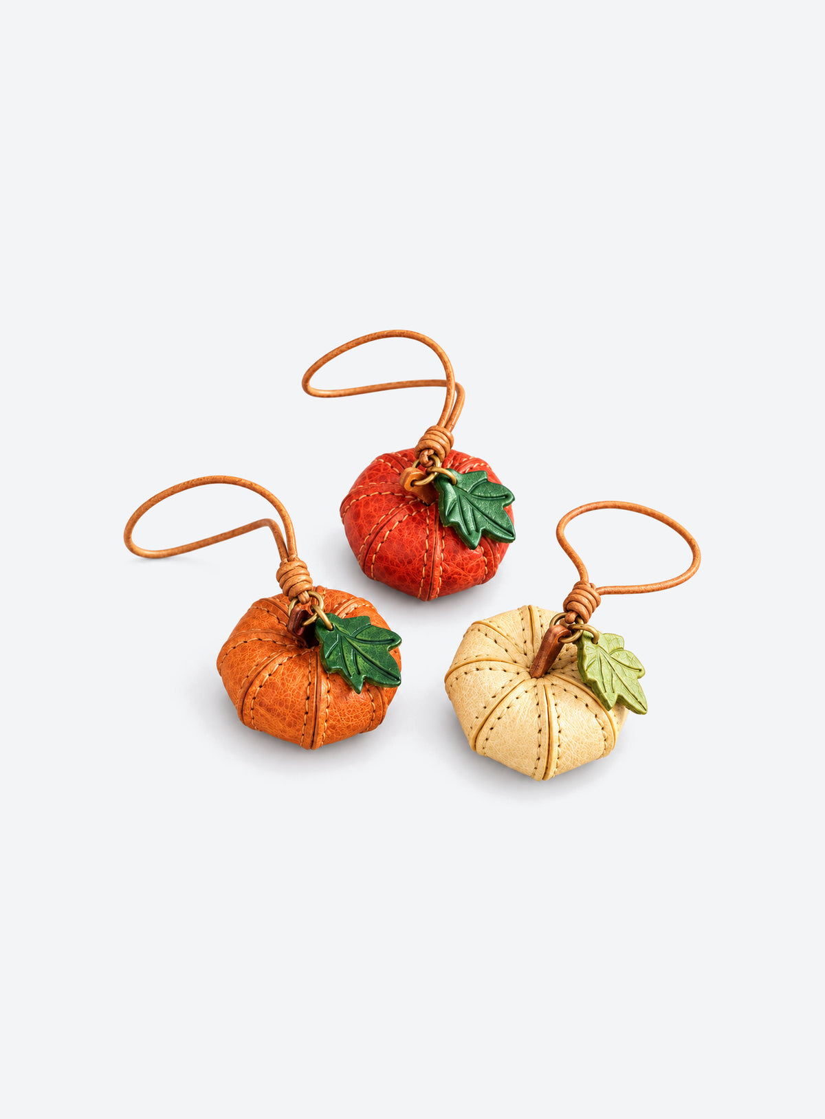 Pumpkin-shaped leather bag charm with stitched panels, a leaf accent, and a hanging loop