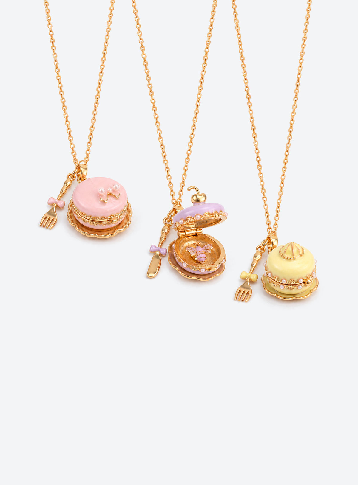 Cake-shaped enamel locket necklace with gold-tone trim and chain, plus a miniature cutlery charm