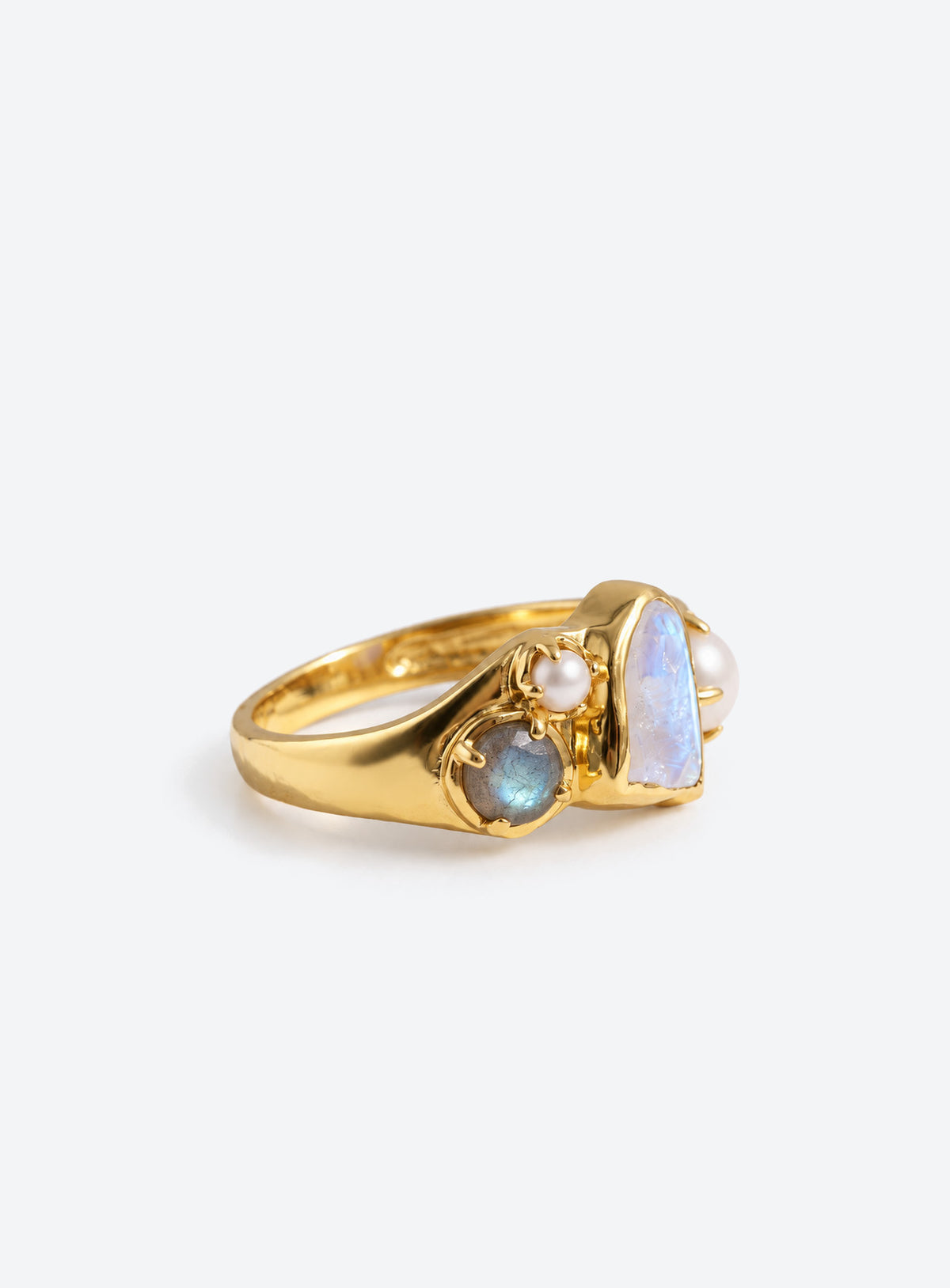 Gold-finish ring with a pale irregular moonstone, white pearls, and small blue-gray stones in an asymmetric cluster