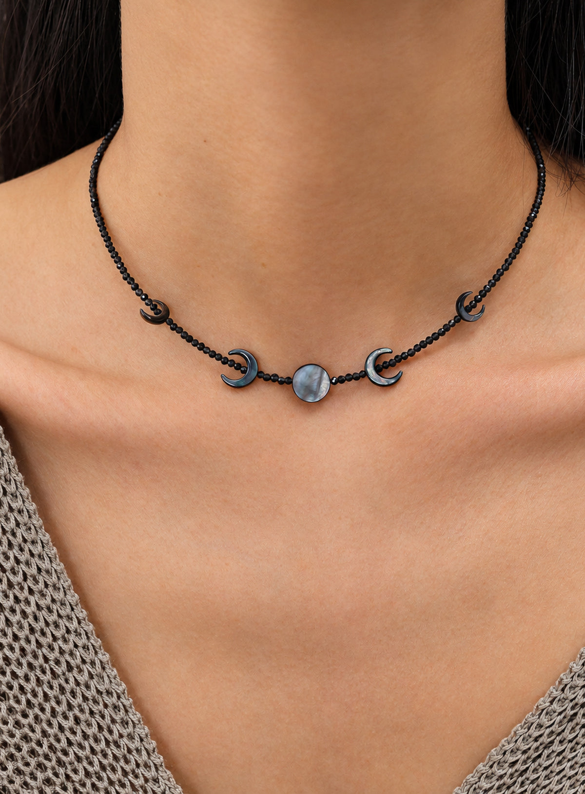 Black beaded necklace with four outward-facing shell crescents around a round center disc and a silver-finish clasp. (Silver)