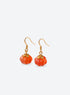 Pair of translucent orange pumpkin earrings with metal leaf details and curved ear hooks