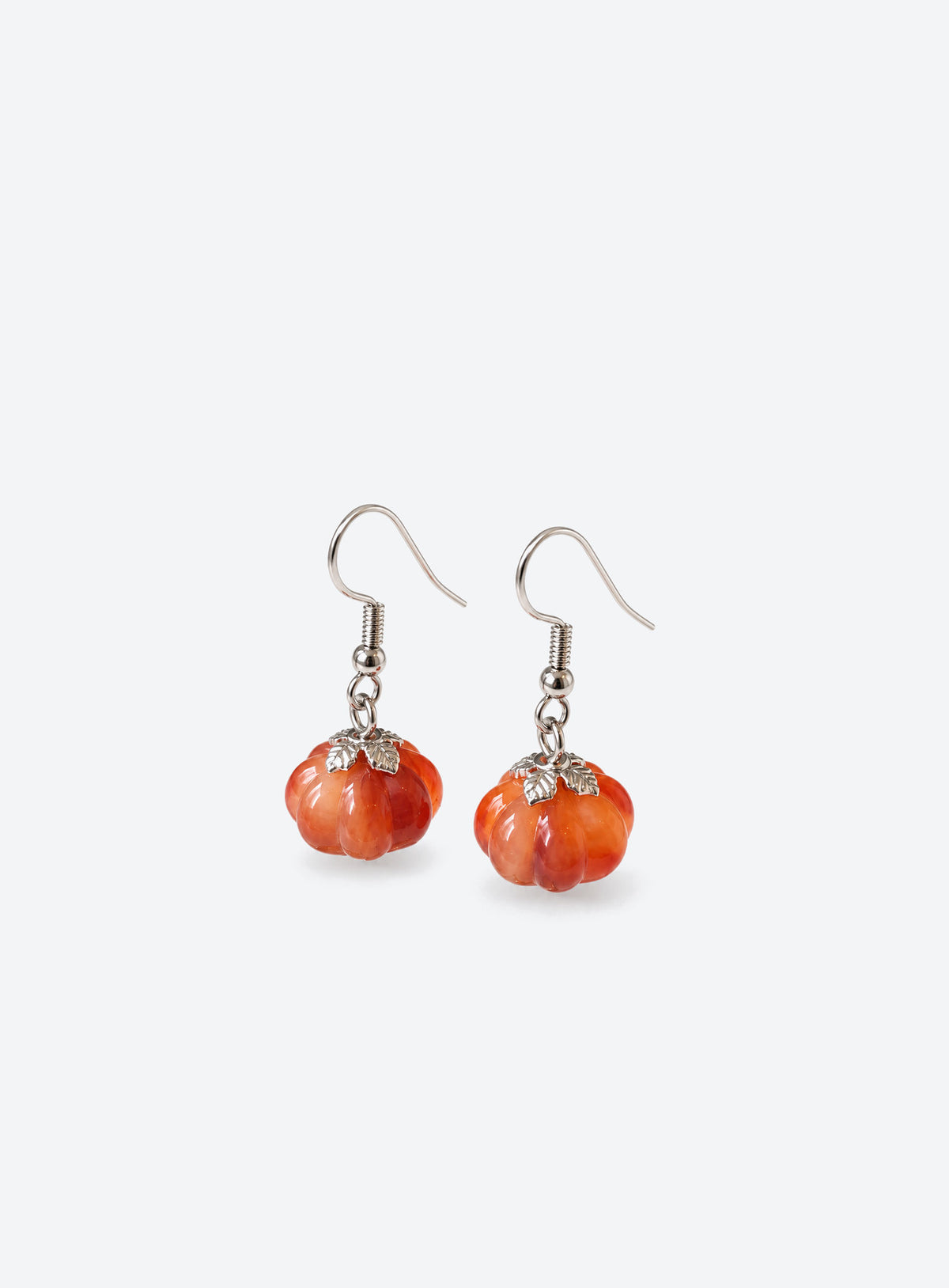 Pair of translucent orange pumpkin earrings with metal leaf details and curved ear hooks