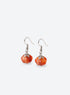 Pair of translucent orange pumpkin earrings with metal leaf details and curved ear hooks