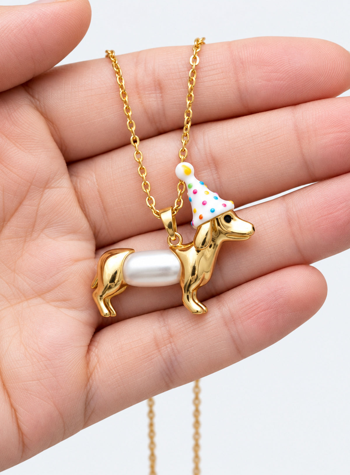 Dachshund pendant necklace with a white pearl body and a white party hat decorated with colored dots