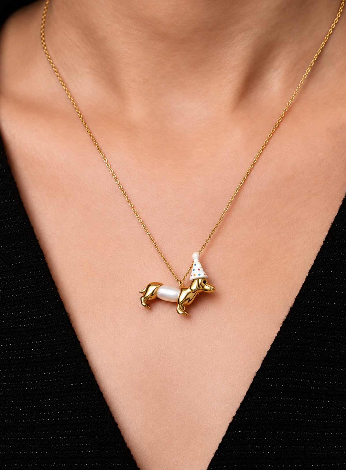 Dachshund pendant necklace with a white pearl body and a white party hat decorated with colored dots