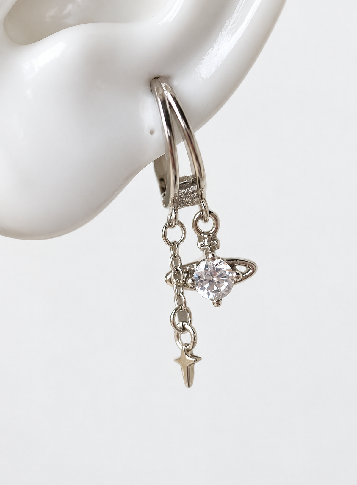 Silver-tone double-layer huggie design with a cubic zirconia planet and chain-hung star