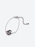 Silver-finish chain bracelet with a dark shell crescent, purple flowers and a black stone accent.