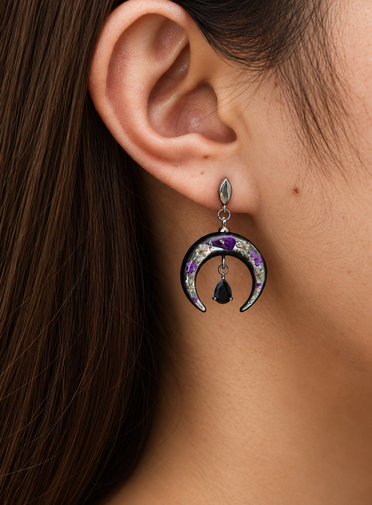 Pair of silver-finish earrings with purple flowers on dark crescents and hanging black teardrop stones.