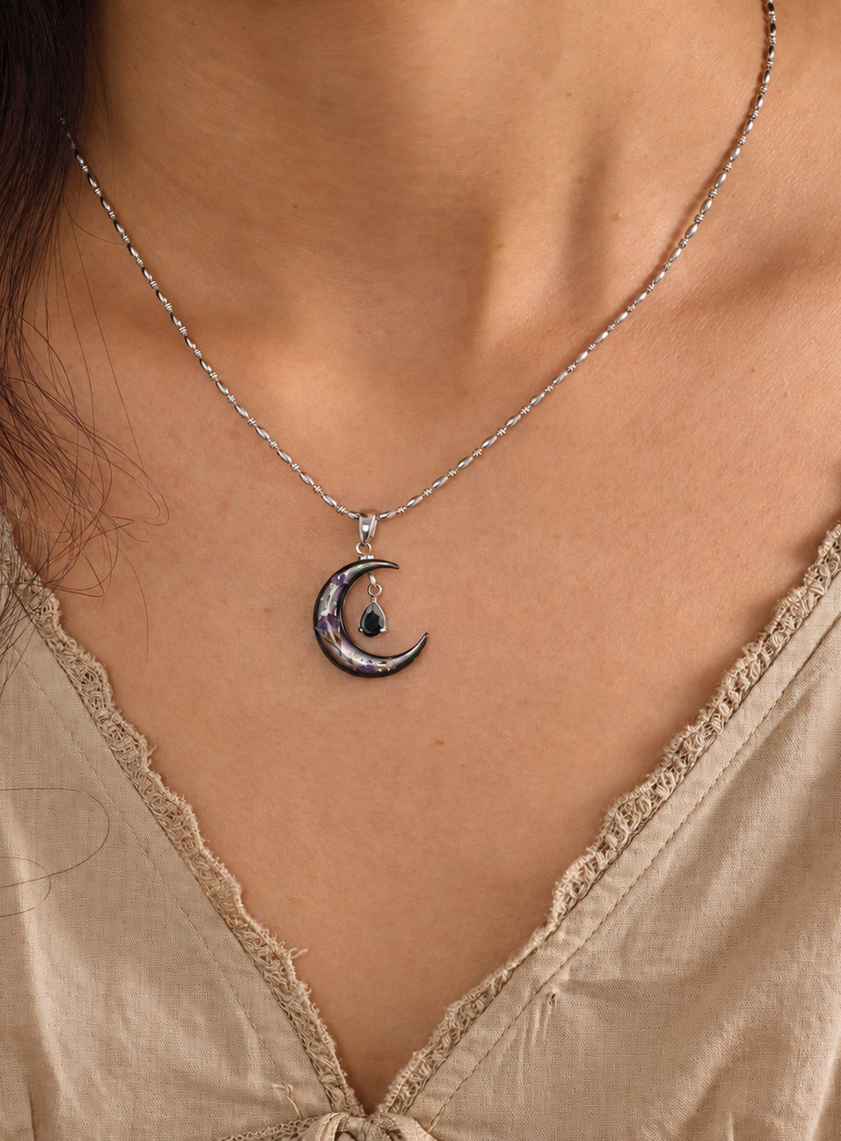 Silver-tone rice bead chain necklace with a dark crescent, purple flowers and a black teardrop