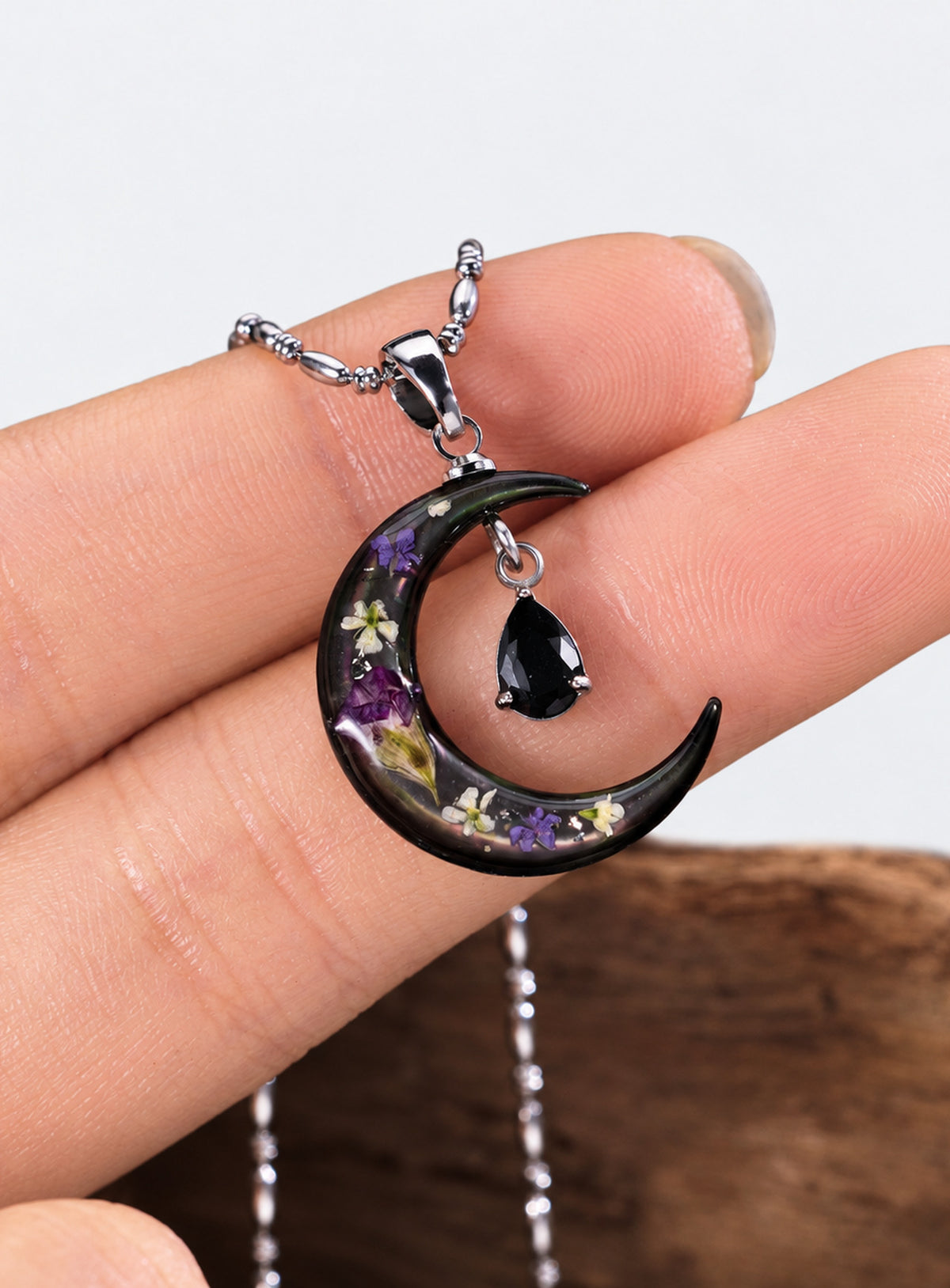 Silver-tone rice bead chain necklace with a dark crescent, purple flowers and a black teardrop